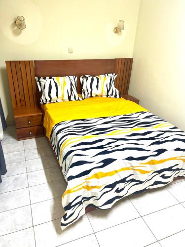 a bedroom with a bed with a yellow and black comforter at Hacienda Residence - Solar Energized in Yaoundé