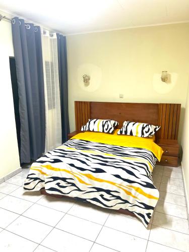 a bedroom with a bed with a black and yellow comforter at Hacienda Residence - Solar Energized in Yaoundé