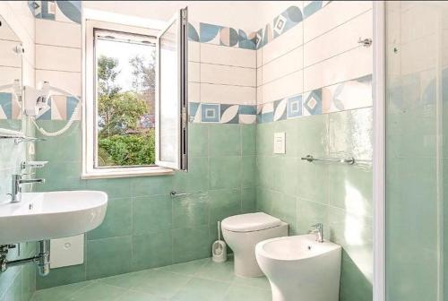 Un baño con lavabo, inodoro y ventana. en Villa Anna, en Palinuro