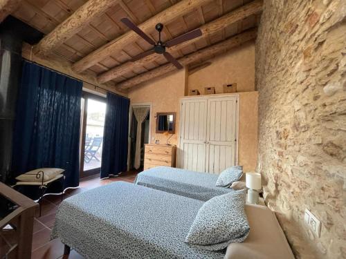 - une chambre avec 2 lits et un mur en pierre dans l'établissement Can Bruguera de Fonteta, à Fonteta