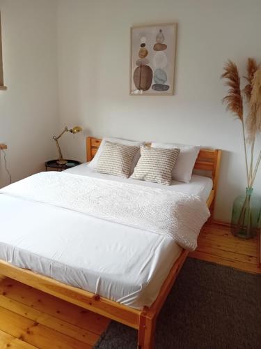 Una cama con sábanas blancas y almohadas en un dormitorio en Daugavas apartamenti, en Ogre