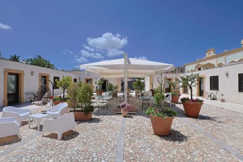 eine Terrasse mit weißen Stühlen und einem Sonnenschirm in der Unterkunft Hotel Villa Lampedusa in Palermo