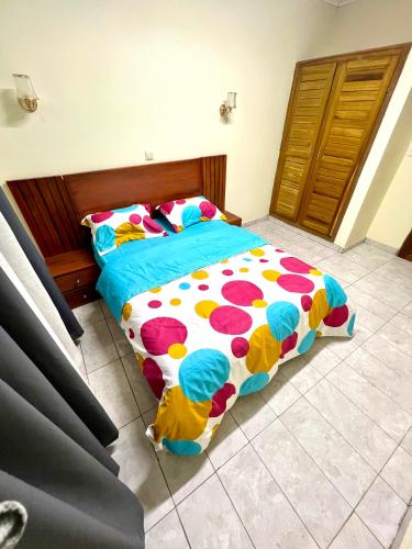 a bedroom with a bed with a colorful comforter at Hacienda Residence - Solar Energized in Yaoundé