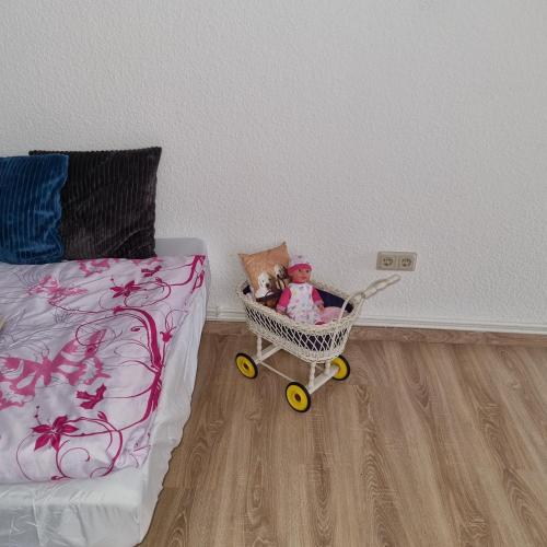 a toy doll in a shopping cart next to a bed at Lehn dich zurück in Mühlhausen