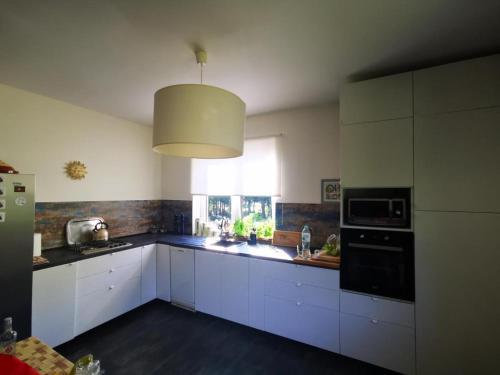 a kitchen with white cabinets and a large window at Dom w lesie in Łukta