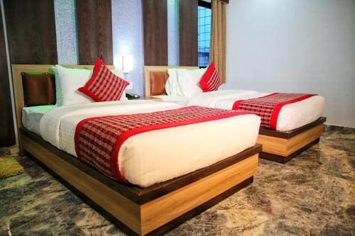 two beds in a hotel room with red and white pillows at Khanal Hotel in Nepālganj