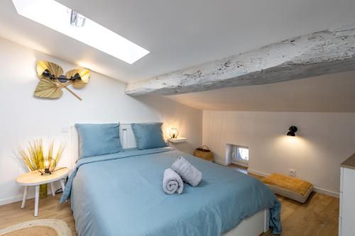 een slaapkamer met een blauw bed en handdoeken bij L'alouette - Duplex Climatisé & Authentique in Castres