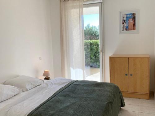 une chambre avec un lit et une porte coulissante en verre dans l'établissement Soleil et détente à Mèze : bel appartement proche plage avec terrasse et jardin - FR-1-604-36, à Mèze