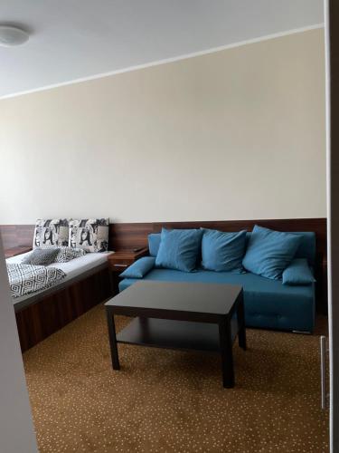 sala de estar con sofá azul y mesa en KOLONIA HOTEL en Świdnica