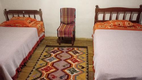 2 camas en una habitación con silla y alfombra en Hospedaje Los Balcones Jumbilla Bongará Amazonas, 
