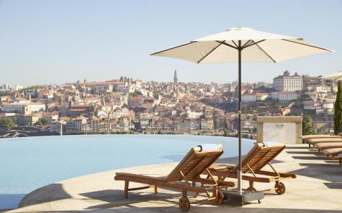 a group of lounge chairs and an umbrella on a pool at The Yeatman in Vila Nova de Gaia