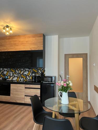 a dining room with a glass table with a vase of flowers at Luxusní Apartmán NMNM Essence in Nové Město na Moravě