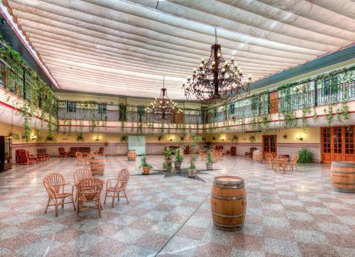 Habitación grande con sillas, mesas y techo. en Hotel Sandra, en Alcalá de Guadaira