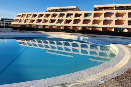 un hôtel avec une piscine devant un immeuble dans l'établissement Studio cosy Port Camargue à 5 minutes de la plage, au Grau-du-Roi