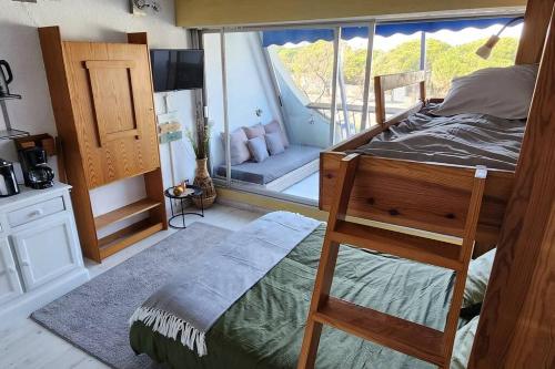 une chambre avec un lit superposé et une grande fenêtre dans l'établissement Studio cosy Port Camargue à 5 minutes de la plage, au Grau-du-Roi
