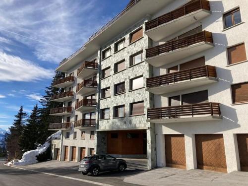 une voiture garée devant un bâtiment dans l'établissement Le nid d’aigle, à Crans-Montana