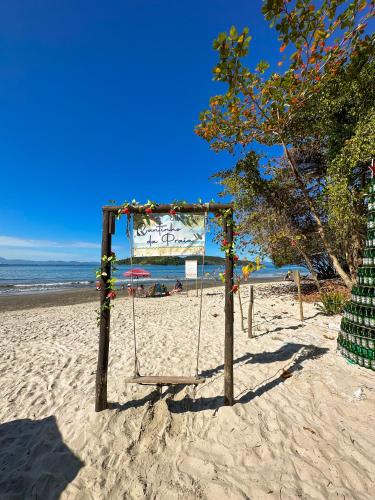 a swing on a beach with the ocean in the background at Pousada Cantinho da Praia in Paraty