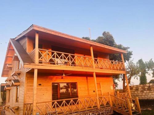 a large wooden house with a large deck at Yellow Pine Luxury Cottage in Jammu