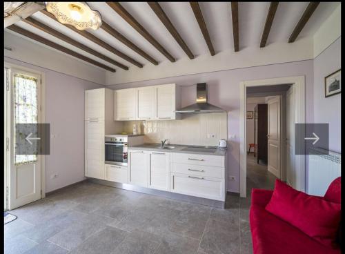 cocina con armarios blancos y sofá rojo en La casa in toscana en Foiano della Chiana