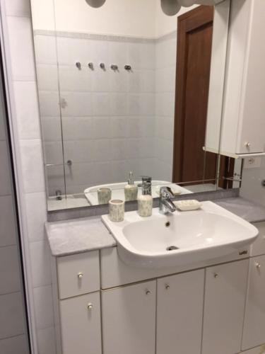 a white bathroom with a sink and a mirror at Foresto Case Vacanza in Volta Mantovana
