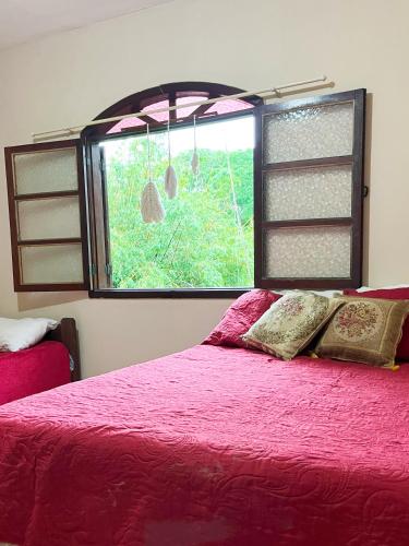 a bedroom with a pink bed and a window at Green House Chalé, hostel e pousada in Saquarema