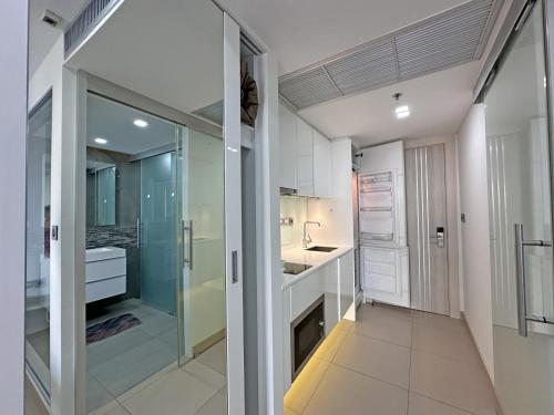 a kitchen with white cabinets and a glass door at Sands Condo Studio 73 by ThaiminatorPattaya in Pattaya South