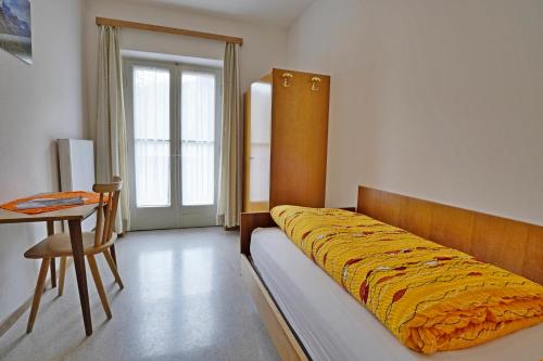 a bedroom with a bed and a table and a chair at Bellavista Schönblick in Casere alte del Piano