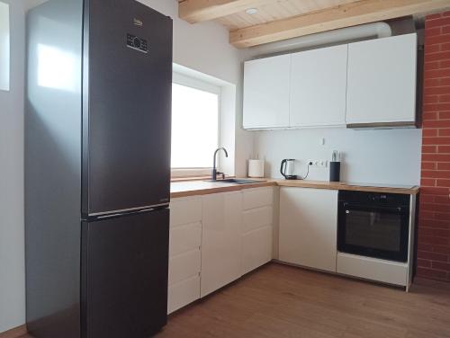 a kitchen with a stainless steel refrigerator and white cabinets at CozyStay in Otepää