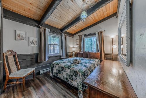 a bedroom with a bed and a chair and windows at Rustling Pines in Ruidoso