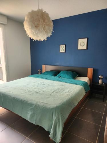 une chambre avec un grand lit avec un mur bleu dans l'établissement Proche Avignon centre, jardin & climatisation 4pers, à Avignon