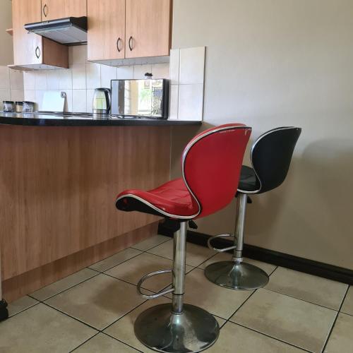 una cocina con 2 sillas rojas frente a un mostrador en FALET ACCOMMODATION, en Midrand