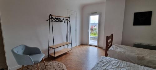 una camera con un letto e una sedia e una finestra di GRANIT COCOON a Saint-Quay-Perros