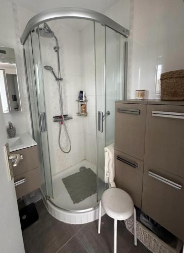 La salle de bains est pourvue d'une douche avec une chaise et un tabouret. dans l'établissement Maison Batz-sur-Mer, plage à 5 minutes, à Batz-sur-Mer