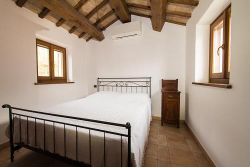 a bedroom with a bed and two windows at Casetta in Pietra in Acqualagna