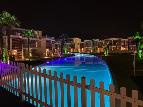 uma piscina em frente a uma cerca à noite em Romantika apartment em Lido di Jesolo