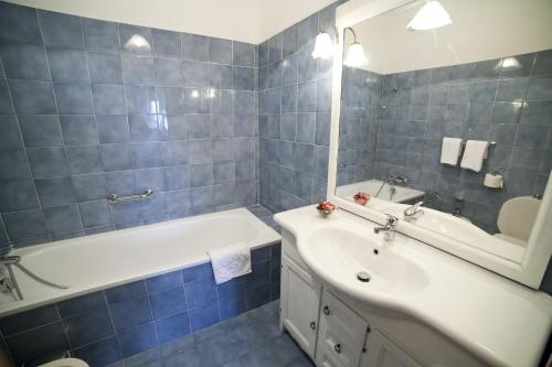 ein Badezimmer mit einer Badewanne, einem Waschbecken und einem Spiegel in der Unterkunft Roman Holidays all'Eur in Rom