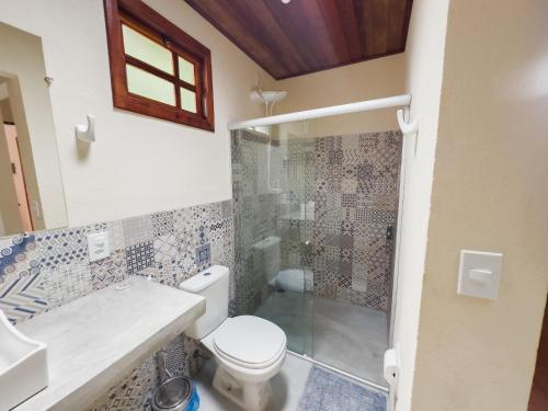 a bathroom with a toilet and a glass shower at Pousada da Fonte in Lençóis