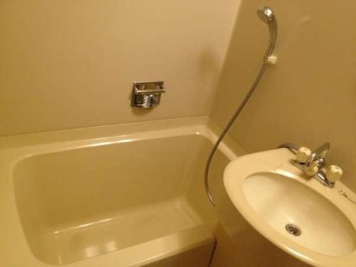 a bathroom with a sink and a tub and a toilet at HOTEL LiVEMAX BUDGET Fuchu in Fuchu