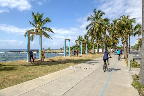 eine Person, die auf einem Bürgersteig in Strandnähe Fahrrad fährt in der Unterkunft La Casa de la Manada in Santo Domingo