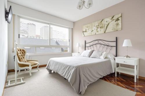 um quarto branco com uma cama e uma cadeira em Apartamento con ascensor, dos habitaciones em La Coruña