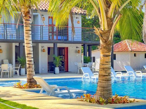 um resort com piscina, palmeiras e cadeiras em Villa Effi em El Porvenir