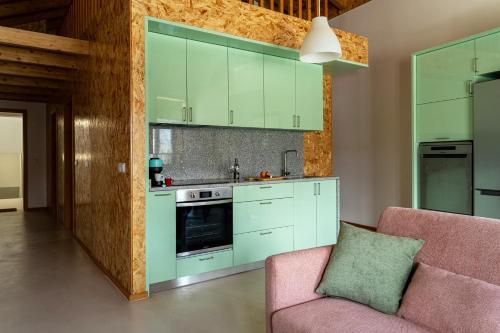 eine Küche mit grünen Schränken und einer rosa Couch in der Unterkunft City Hall Apartments in Vila Real