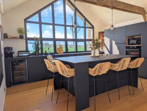 a kitchen with a large black island with chairs at Villa vue Mer -5 mn des plages - grand jardin-cuisine d'été- 4 chambres in Planguenoual