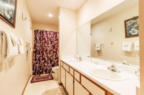 a bathroom with a sink and a toilet and a mirror at Walk-in Eagles Nest Condo with Pool and Hot Tub near Silver Dollar City in Branson