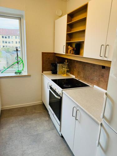 a kitchen with white cabinets and a stove and a window at Cozy Apartment Aarhus C in Aarhus