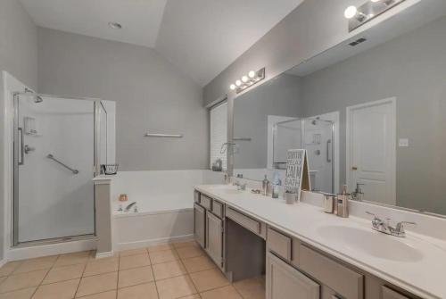 a bathroom with two sinks and a shower and a tub at Frisco Spacious & Cozy Bling Home by Aya in Frisco