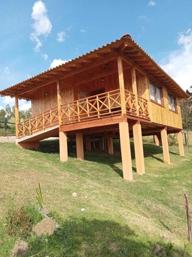 ein großes Holzhaus auf einem Grasfeld in der Unterkunft Cabaña Colibri in Paipa