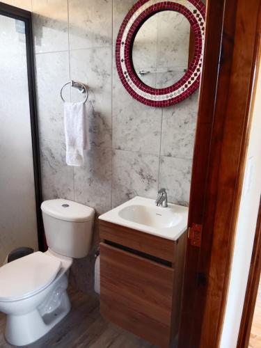 a bathroom with a toilet and a sink and a mirror at Cabaña Colibri in Paipa
