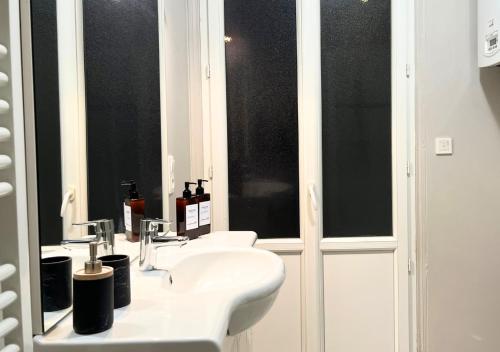 a bathroom with a sink and two windows at Le Charme D'Antan in Évreux