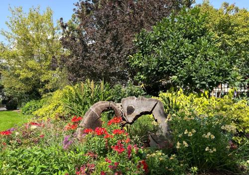 a garden with a statue in the middle of flowers at Le Charme D'Antan - Terrasse - Balcon - Hypercentre Evreux in Évreux